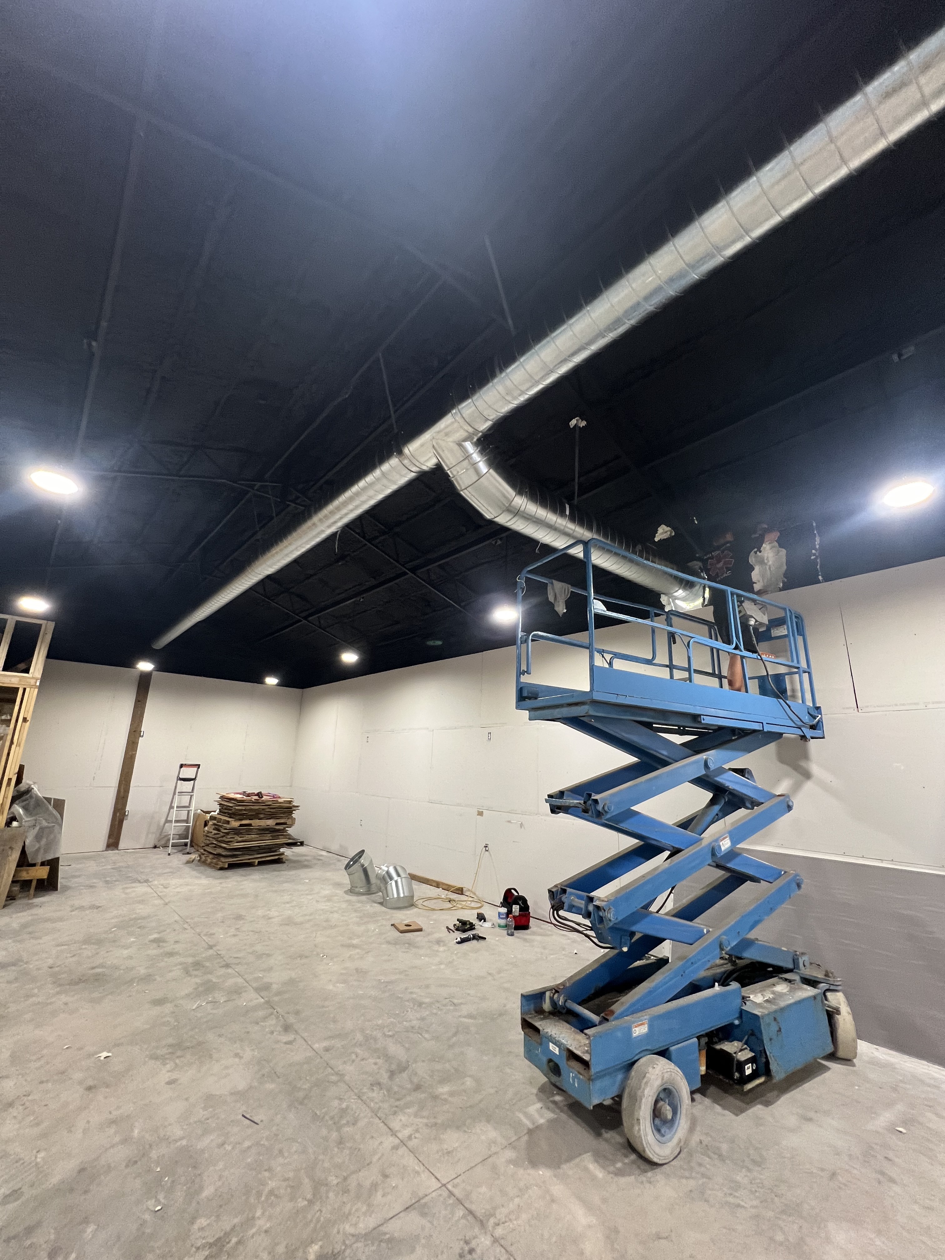 Air Medics technician on a scissor lift installing commercial ductwork